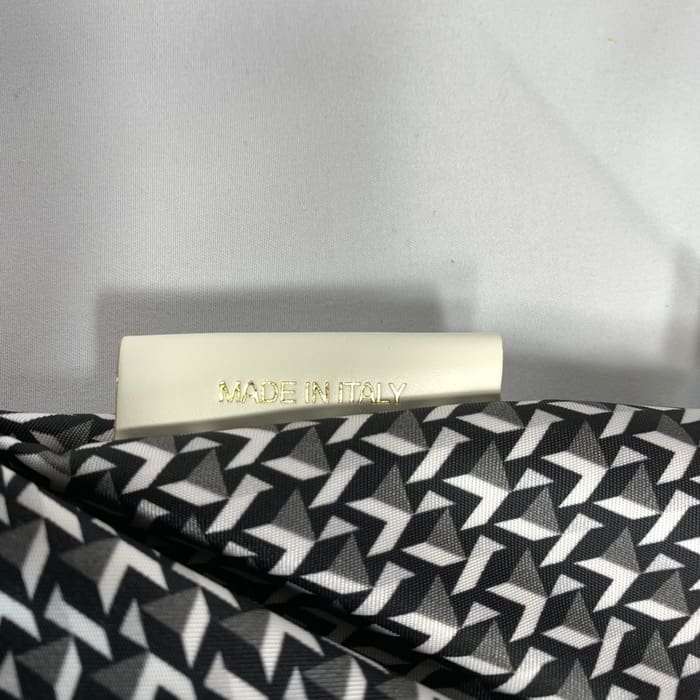 Ang itim at puting geometric na mini duffel na tela ni ROBERTA PIERI na may puting label na nagbabasa ng "MADE IN ITALY" sa mga gintong titik. Ang background ay plain white.