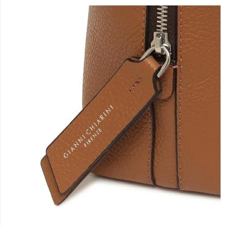 Close-up ng brown leather bag ni GIANNI CHIARINI. Mayroon itong metal zipper at leather tag na may nakasulat na "GIANNI CHIARINI FIRENZE" sa puti. Ginawa ito sa Italya at nagpapakita ng walang-hanggang kagandahan ng Italyano.